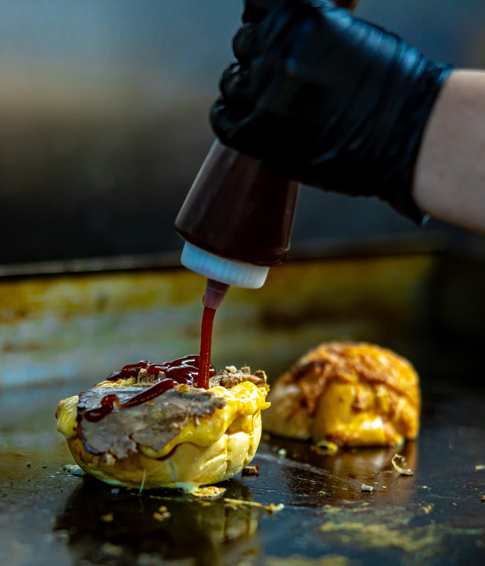 House barbecue sauce poured over sliced brisket and melted cheese on the griddle